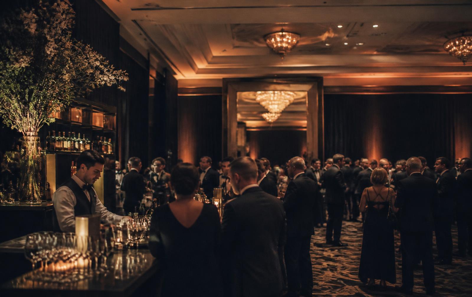 Guests gathered around an elegant bar at a large hotel ballroom event